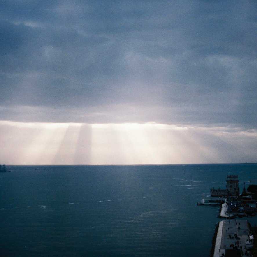 Sunlight breaking through clouds over the ocean in Lisbon, Portugal near the Torre de Belém