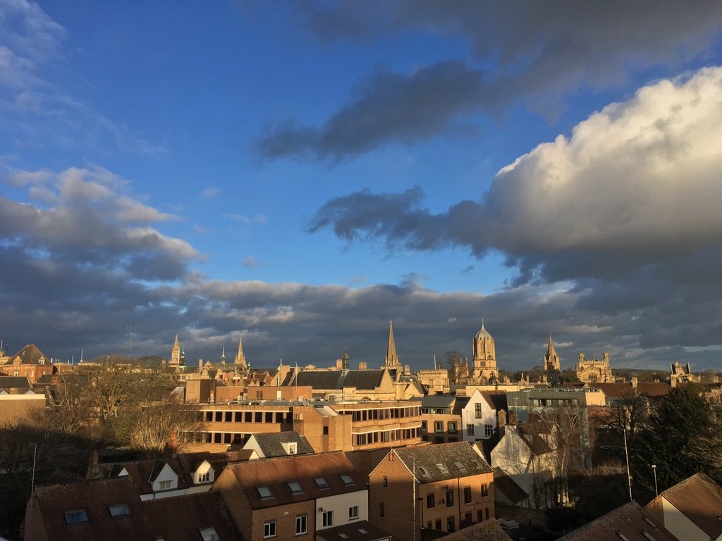Rooftop view of an old European city with church spires under a dramatic blue and cloudy sky